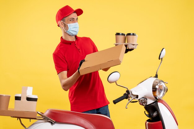 Mensajero masculino de vista frontal en uniforme con caja de café y comida en el servicio pandémico amarillo trabajo virus de trabajo uniforme covid