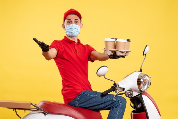 Mensajero masculino de vista frontal en uniforme y máscara con café en el trabajo de servicio amarillo pandemia covid- virus de alimentos color de trabajo