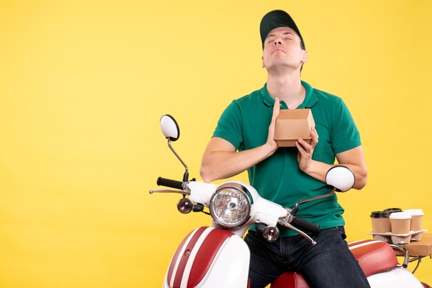 Mensajero masculino de la vista frontal en uniforme que sostiene el pequeño paquete de comida en amarillo