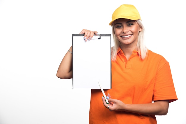 Mensajero mujer apuntando al cuaderno vacío sobre fondo blanco. Foto de alta calidad