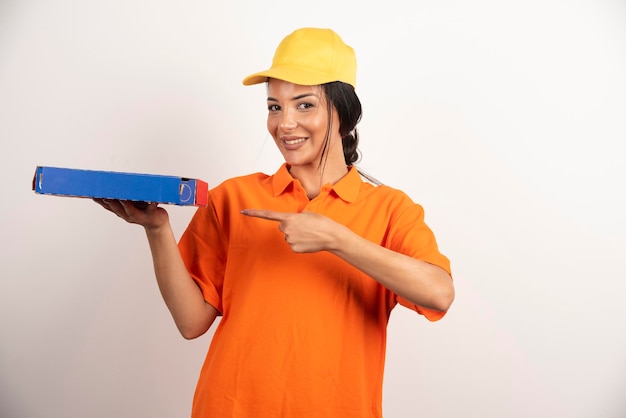 Mensajero mujer apuntando sobre cartón de pizza.