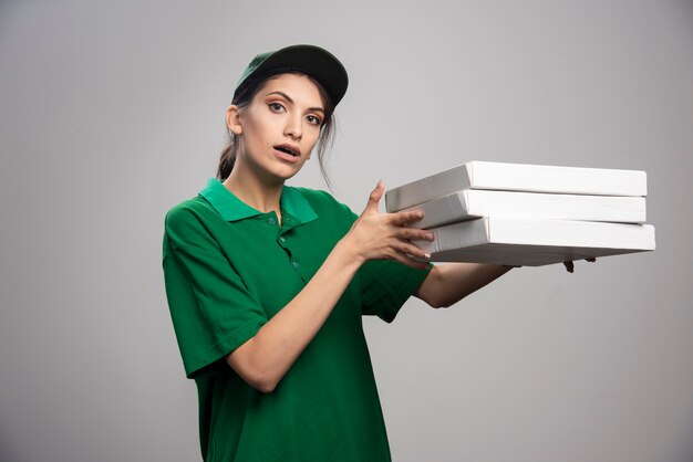 Mensajero mujer joven posando con cajas de pizza