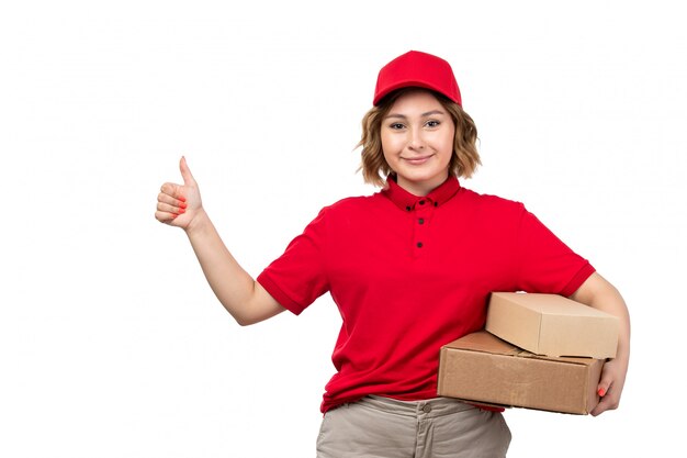 Un mensajero de mujer joven de vista frontal en camisa roja gorra roja sosteniendo cajas de entrega