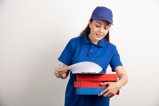 Foto gratuita mensajero mujer mirando cartón de pizza y portapapeles