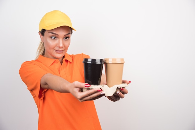 Mensajero mujer rubia sosteniendo dos tazas de café.