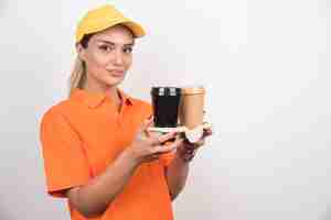 Foto gratuita mensajero mujer sosteniendo dos tazas de café en la pared blanca.