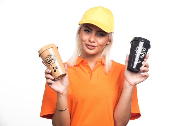 Mensajero mujer sosteniendo dos tazas de café sobre fondo blanco. Foto de alta calidad