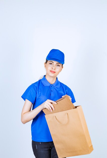 Mensajero mujer tomando la caja de cartón de la bolsa de papel artesanal.