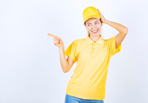 Mensajero mujer en uniforme amarillo apuntando a algún lugar.