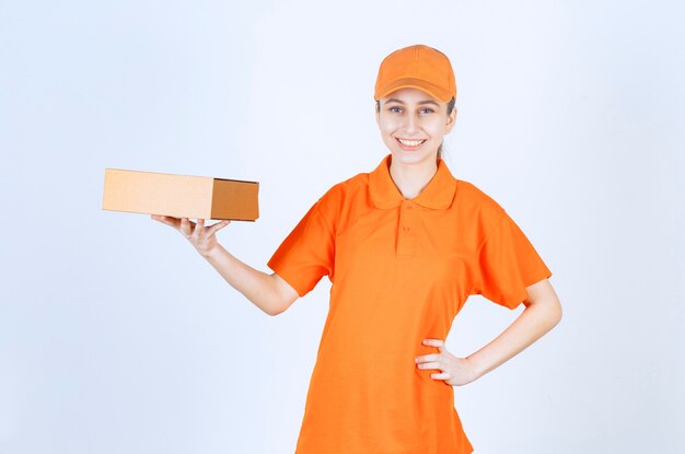 Mensajero mujer en uniforme amarillo entregando una caja de cartón.