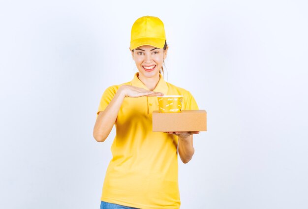 Mensajero mujer en uniforme amarillo haciendo una entrega de comida para llevar.