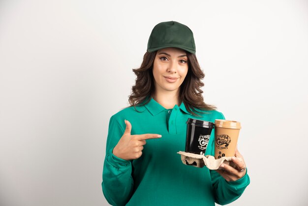 Mensajero mujer en uniforme apuntando a café para llevar.