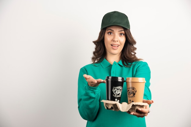 Mensajero mujer en uniforme mostrando tazas de café.