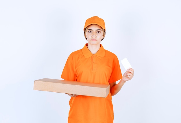 Mensajero mujer en uniforme naranja sosteniendo una caja de cartón y presentando su tarjeta de visita