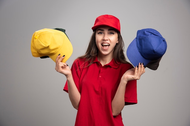 Mensajero mujer en uniforme rojo con gorras de colores.