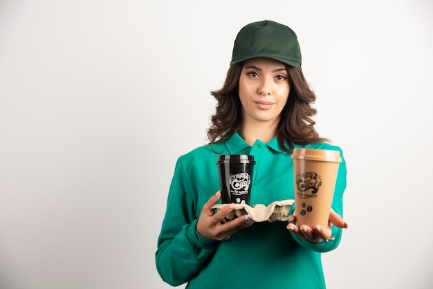 Mensajero mujer en uniforme verde con tazas de café.