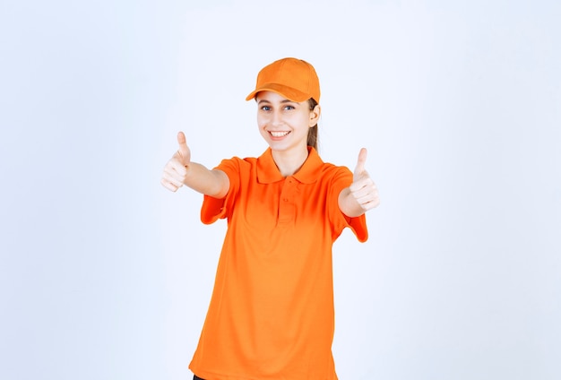 Mensajero mujer vistiendo uniforme naranja y gorra mostrando el pulgar hacia arriba