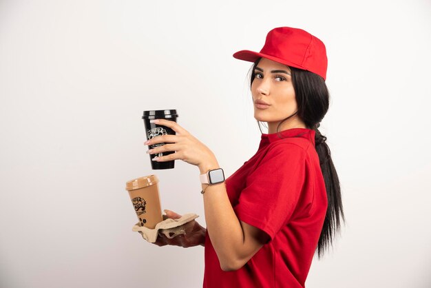 Mensajero serio posando con dos tazas de café. Foto de alta calidad