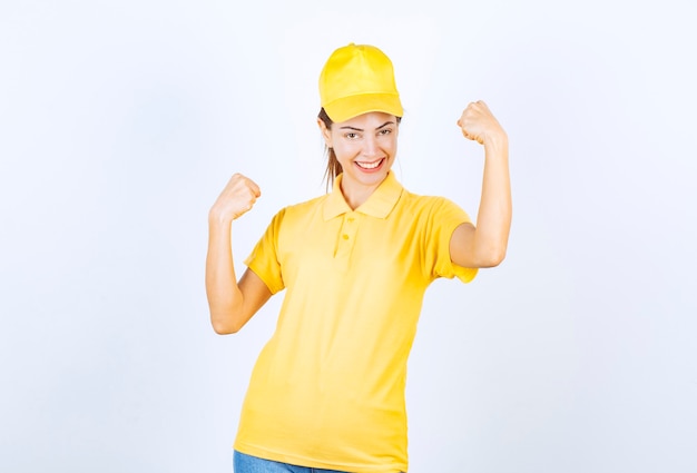 Mensajero de sexo femenino en uniforme amarillo que demuestra los músculos de su brazo.