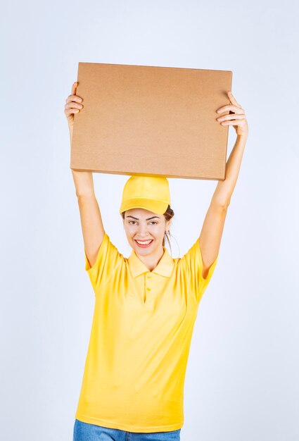 Mensajero de uniforme amarillo entregó un paquete de cartón a la dirección correcta.