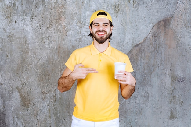 Mensajero en uniforme amarillo sosteniendo un vaso desechable.