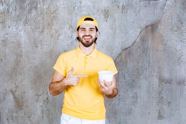 Mensajero en uniforme amarillo sosteniendo un vaso de plástico