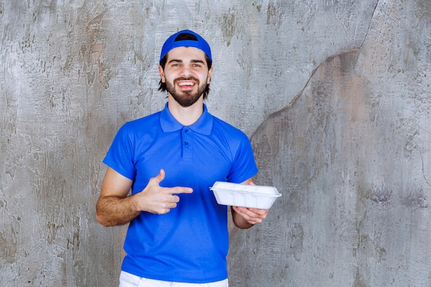 Mensajero en uniforme azul sosteniendo una caja de comida para llevar de plástico