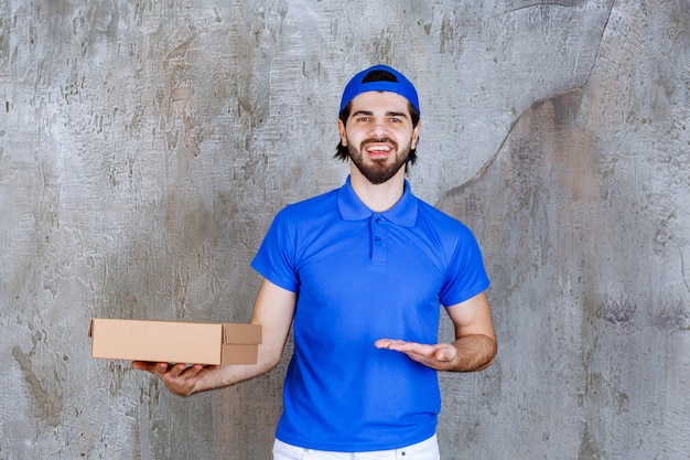Mensajero en uniforme azul sosteniendo una caja de comida para llevar