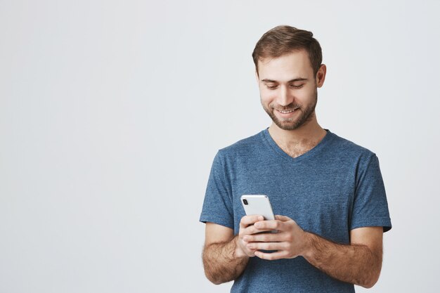 Mensajes de texto guapo chico caucásico, utilizando el teléfono móvil