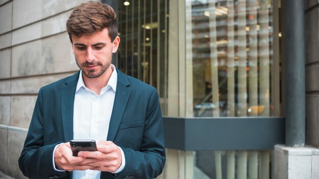 Mensajes de texto de joven empresario en el teléfono inteligente