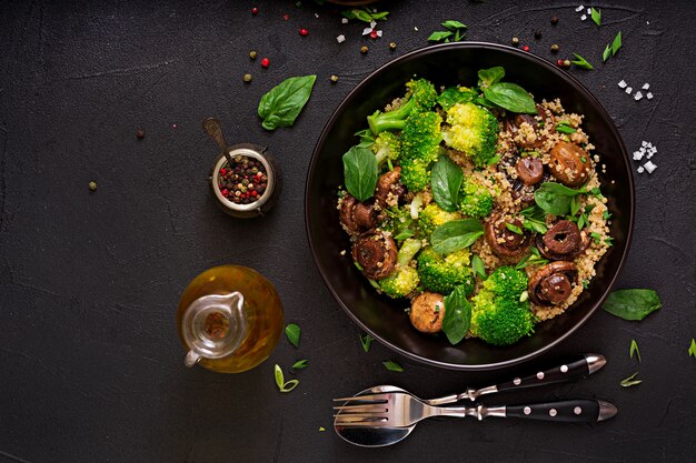 Menú dietético Ensalada vegana saludable de verduras - brócoli, champiñones, espinacas y quinua en un tazón. Endecha plana. Vista superior