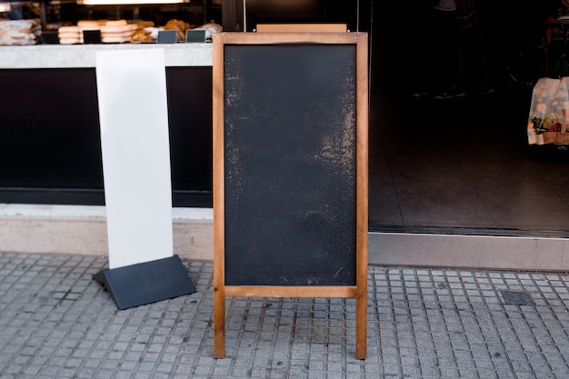 Foto gratuita menú de pizarra en blanco y cartelera blanca frente al restaurante en la calle