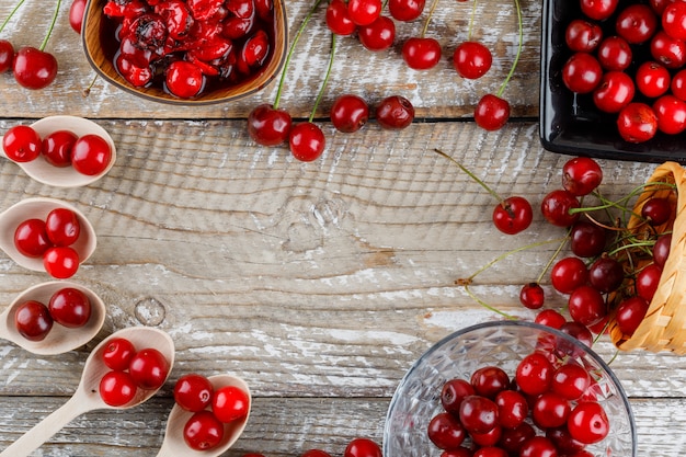 Mermelada de cerezas en un tazón con cerezas frescas en madera