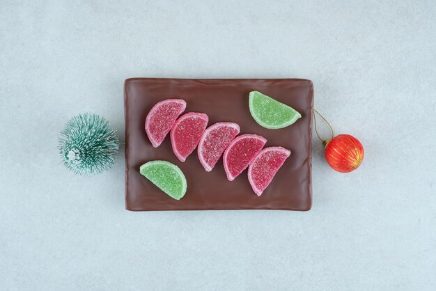 Mermelada dulce con bola de Navidad y árbol en plato oscuro.