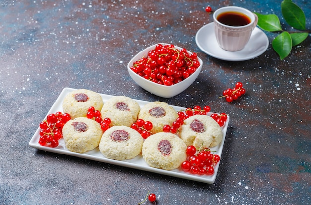 Mermelada de grosella roja rústica casera rellenando galletas con coco y una taza de té