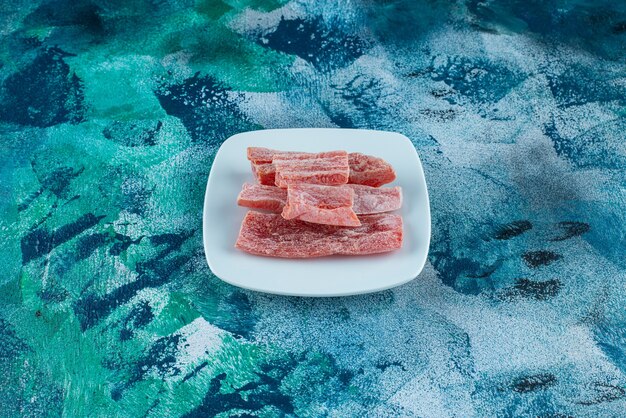 Mermelada roja en un plato sobre la superficie azul