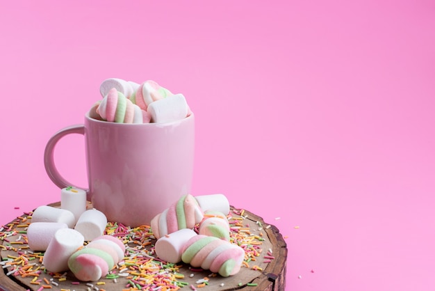 Una mermelada de vista frontal dentro de la taza junto con partículas de caramelo sobre madera y color rosa, azúcar dulce