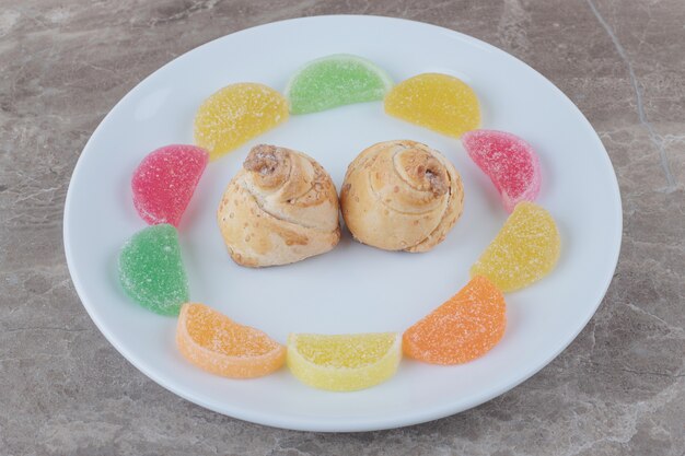 Mermeladas alrededor de pasteles diminutos en una bandeja de mármol