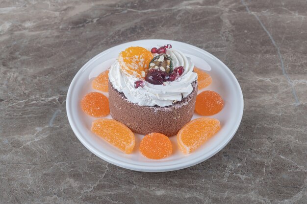 Mermeladas alrededor de un pequeño pastel en un plato sobre la superficie de mármol