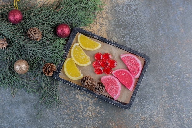 Mermeladas dulces en platos oscuros con piñas navideñas. Foto de alta calidad