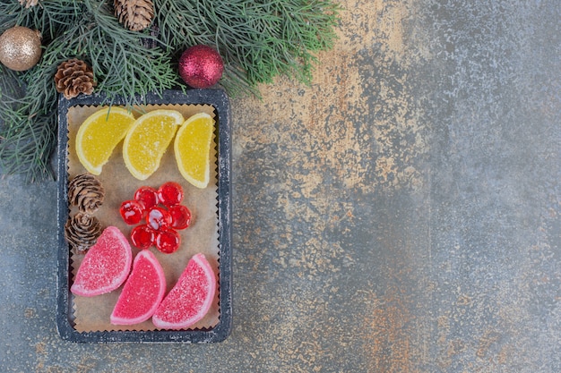 Mermeladas dulces en platos oscuros con piñas navideñas. Foto de alta calidad