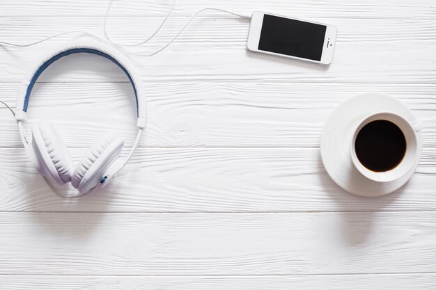 Mesa con auriculares, café y teléfono