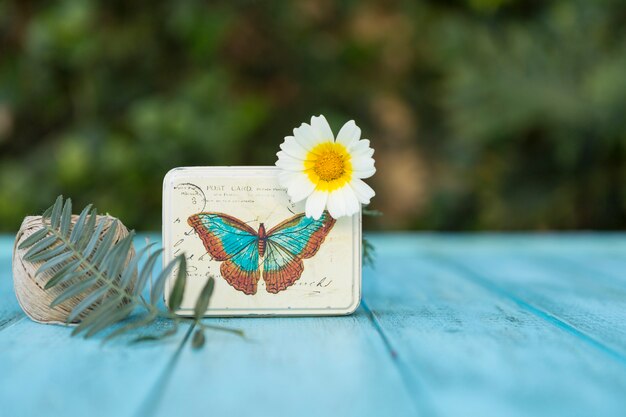 Mesa azul con caja decorativa y margarita