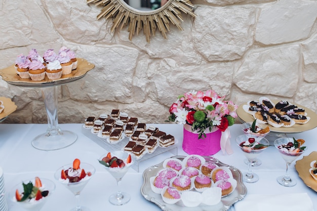 Mesa de bar servida de una variedad de dulces como tiramisú, canutillos y pastelitos