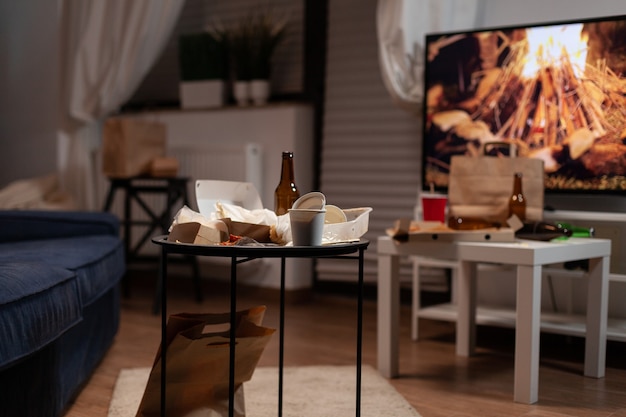 Foto gratuita mesa de basura con botella de bebida de cerveza vacía y comida basura colocada en la sala de estar