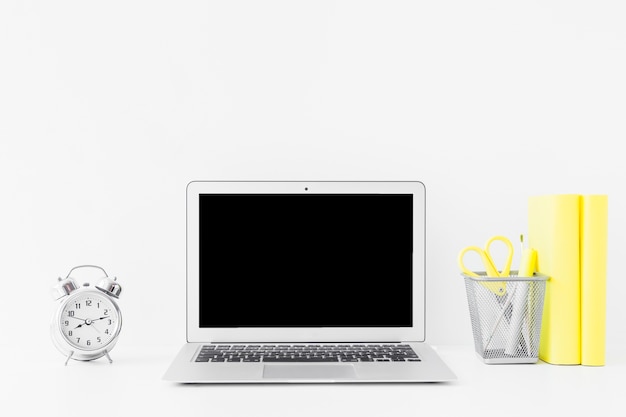 Mesa blanca con laptop y cuadernos