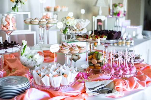 Mesa con deliciosos dulces cubiertos con seda rosa