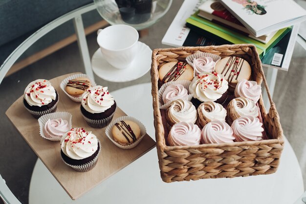 Una mesa de desayuno con una taza de café, dulces, malvaviscos y galletas.