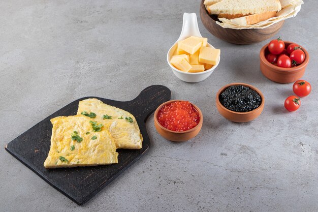 Mesa de desayuno con tortilla y caviar colocada sobre una superficie de piedra.