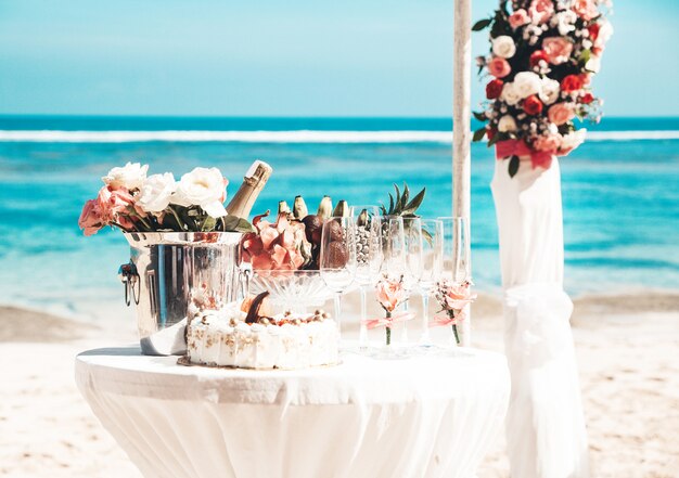 mesa elegante de boda con frutas tropicales y pastel en la playa